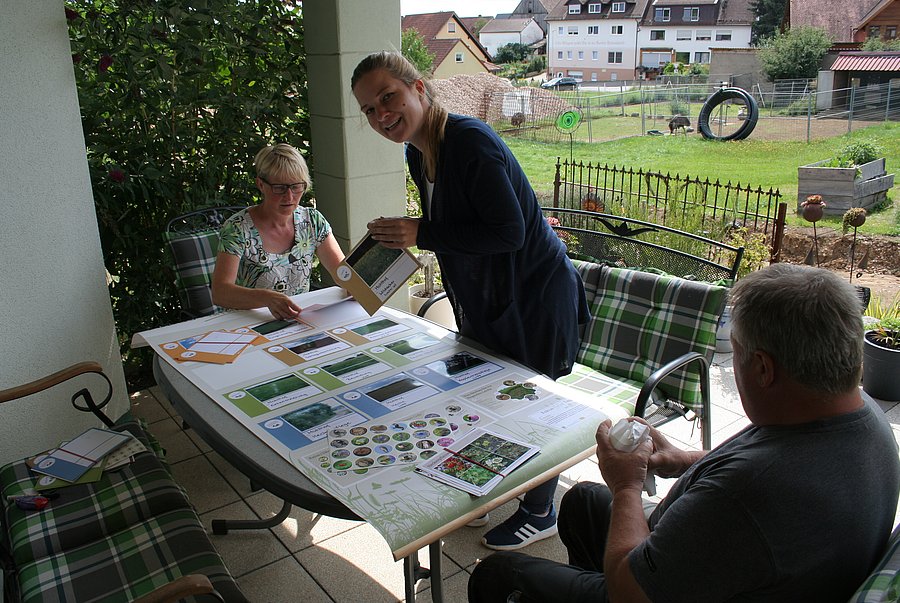 Drei Personen basteln ein Plakat auf einem Tisch.