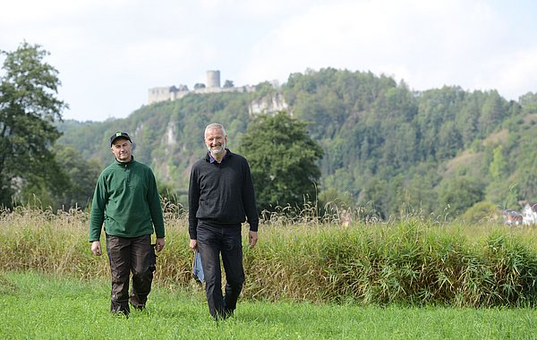 Ein Landwirt und ein Berater laufen auf einer grünen Wiese