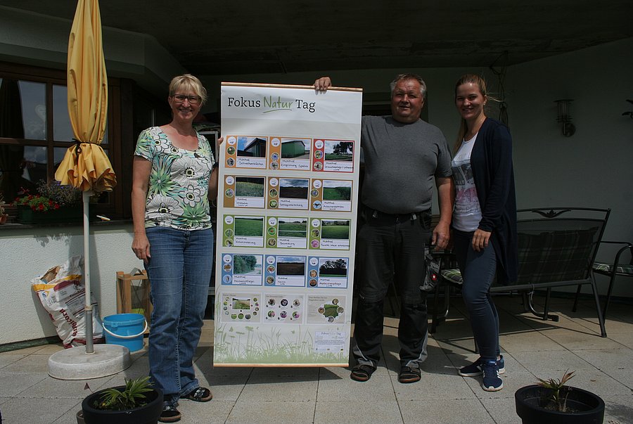 Drei Personen halten ein Plakat hoch.