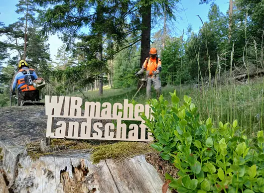 WIR machen Landschaft Schriftzug vor mähenden Personen
