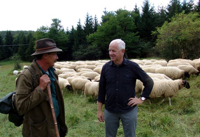 Ein Schäfer und ein Mann im Gespräch, die Schafe weiden im Hintergrund